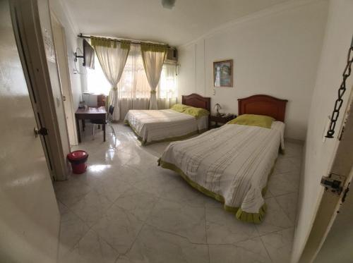 a bedroom with two beds and a desk and a window at Hotel Lord by Croma in Cúcuta