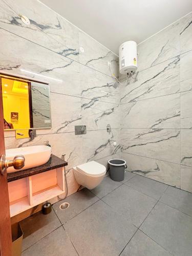 baño con aseo y pared de mármol en Banana Leaf, en Dehradun
