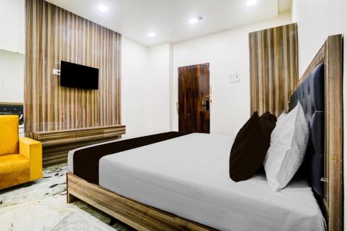 a bedroom with a large bed and a yellow chair at Super Collection O Ulhasnagar Birla Temple Formerly Hotel Yash Residency in Ulhasnagar