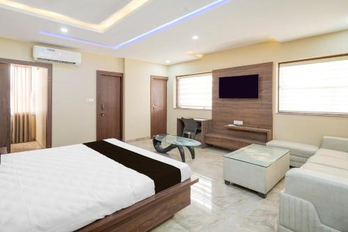 a bedroom with a bed and a couch and a tv at Collection O Ranipur - Dhaney Crossway Formerly Saroj Inn in Bhāda