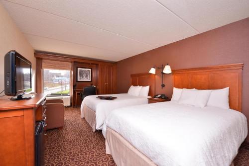 a hotel room with two beds and a flat screen tv at McKnight Hotel in Pittsburgh