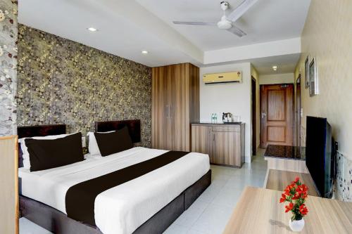 デヘラードゥーンにあるSuper Townhouse Oak ONGC Crossway Formerly Hotel Gold Stone Comfortのベッドルーム1室(大型ベッド1台、花のテーブル付)