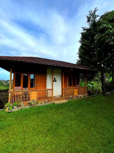 a small house with a porch and a green yard at Villa Kayu Danke in Ciguntur