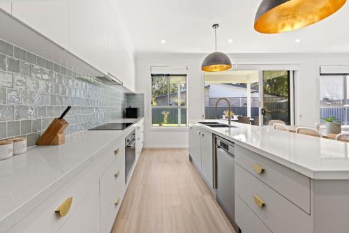 a kitchen with white cabinets and a large white counter top at Callala Chill Jervis Bay - Short Walk to Creek in Callala Bay