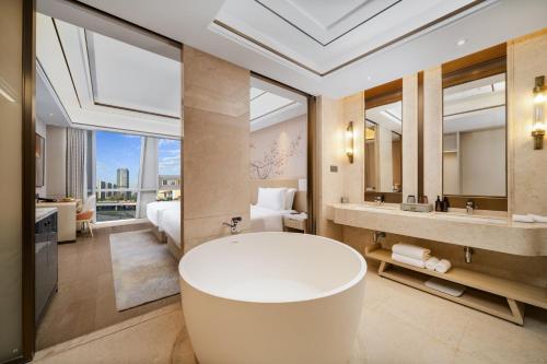 a large bathroom with a tub and a bedroom at Landison Plaza E-Fashion Hotel Hangzhou in Hangzhou