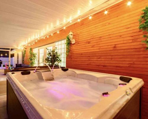 een groot bad in een kamer met een houten muur bij The Flamingo*4bed*pool*jacuzzi*foosball in Valrico