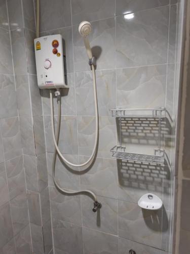 a shower with a hose attached to a wall at Bangtao Mango House in Bang Tao Beach