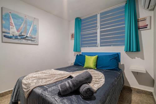 a small bedroom with a bed with blue curtains at Beach Side House Amazing For Family and Group by PH in Luquillo