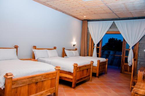 Dos camas en una habitación con ventana. en Babylon Lodge, en Marangu