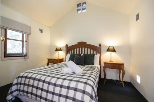 ein Schlafzimmer mit einem Bett mit einer karierten Decke in der Unterkunft Petersons Wines Dairy Cottage in Pokolbin