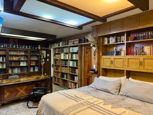 a bedroom with a bed and a desk and book shelves at SUITE 0, Centro de Cuauhtémoc Chihuahua in Cuauhtémoc