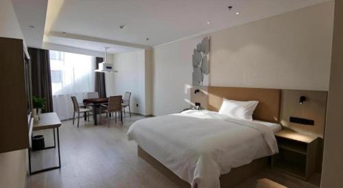 a bedroom with a large bed and a dining room at GreenTree Inn Express Fuzhou Linchuan District Gandong Auto City in Shiliting