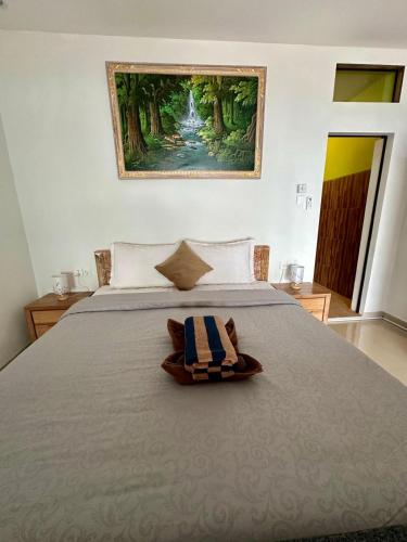 a bedroom with a bed with a painting on the wall at Dewata Beach House in Amed