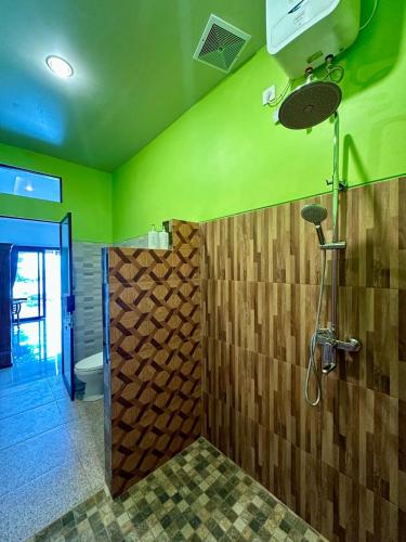a bathroom with green walls and a shower at Dewata Beach House in Amed