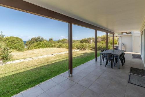 a patio with a table and chairs and a large window at Blueys Bliss 2 in Blueys Beach