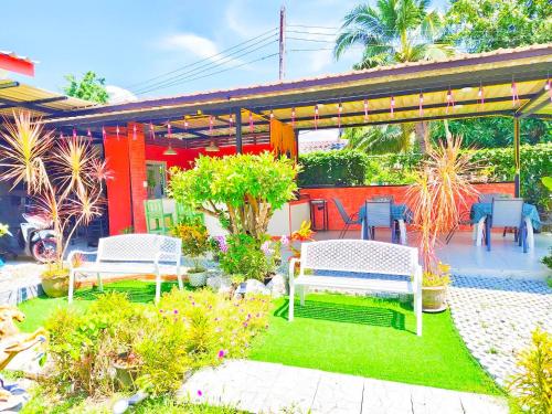 a garden with two white benches and plants at Suki Palm in Ban Bang Chak