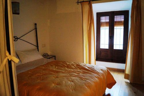a bedroom with a bed and a window and a door at Casa de la Placeta del Rincón in Moclín