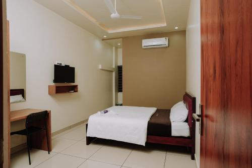 CalicutAtland Residency的一间卧室，里面有一张床、一张桌子和一台电视。