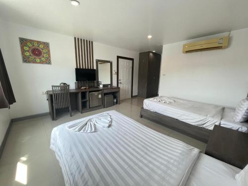 a bedroom with two beds and a desk and a television at Cocoon Patong Hotel in Patong Beach