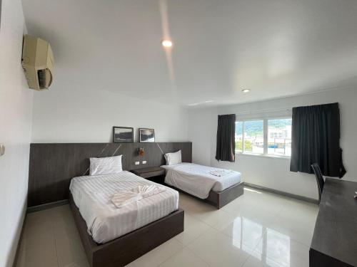 a hotel room with two beds and a window at Cocoon Patong Hotel in Patong Beach