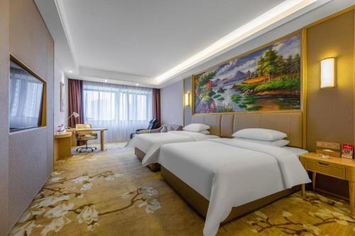 twee bedden in een kamer met een schilderij aan de muur bij Vienna Hotel Jiangxi Yongxin Shizheng Square in Yongxin