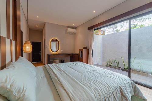 a bedroom with a large bed and a large window at Jiwandari House Bali in Darmasaba