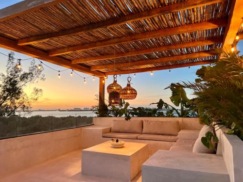 a patio with a couch and a table and a sunset at Exclusive apt with private rooftop & amazing views in Cancún