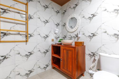 a bathroom with white marble walls and a sink at La Semaya Beach Villas in Nusa Penida