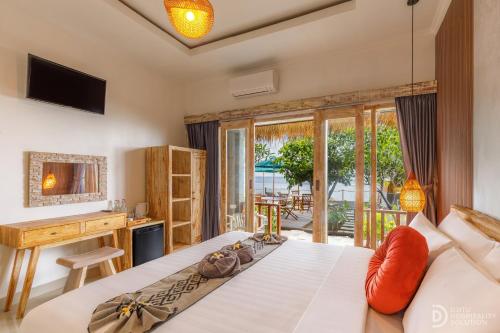 a bedroom with a bed and a desk and a television at La Semaya Beach Villas in Nusa Penida