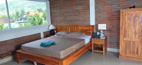 a bedroom with a bed and a brick wall at Amed Sari Beach Guesthouse in Amed