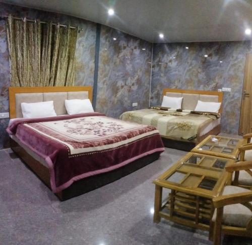 a bedroom with two beds and a table at Hotel Neilkanth in Dhanaulti