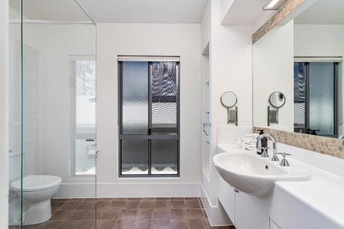 une salle de bain blanche avec un lavabo et des toilettes dans l'établissement Palm Beach Perfection - Luxe Coastal Escape, à Gold Coast