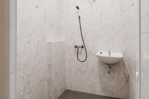 a white bathroom with a shower and a sink at Urbanview Hotel Bonetta Lampung by RedDoorz in Kedaton