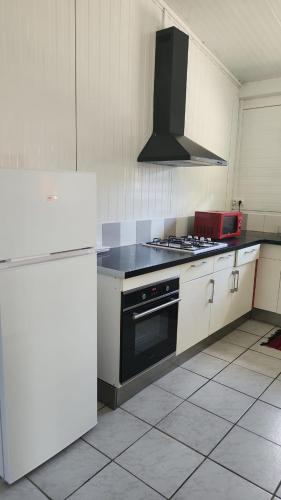 a kitchen with white cabinets and a black stove top oven at La Villa Ti'Lau in Saint-Laurent du Maroni