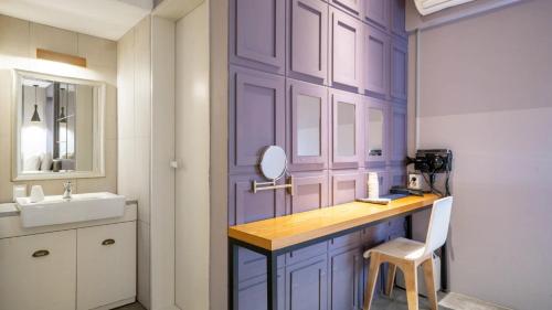 a purple bathroom with a sink and a mirror at NU Hotel in Cheonan