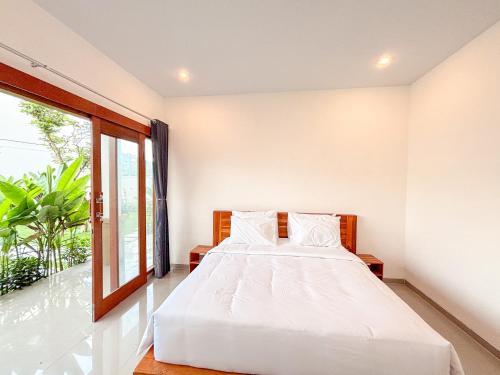 une chambre avec un lit blanc et une fenêtre dans l'établissement Oemah Maha, à Tanah Lot