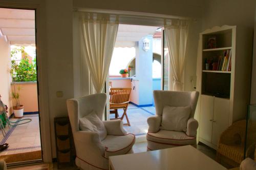 ein Wohnzimmer mit zwei Stühlen und einem Tisch in der Unterkunft Apartamento Playa Muralla in El Puerto de Santa María