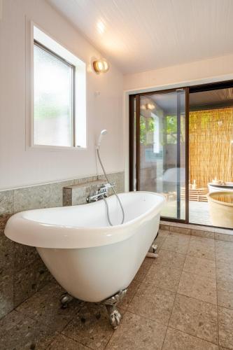 a white bath tub in a bathroom with a window at Hakone Villa with your private hot spring! in Hakone