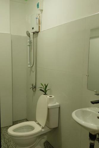 a white bathroom with a toilet and a sink at Felicitas Guest House- Siargao in General Luna
