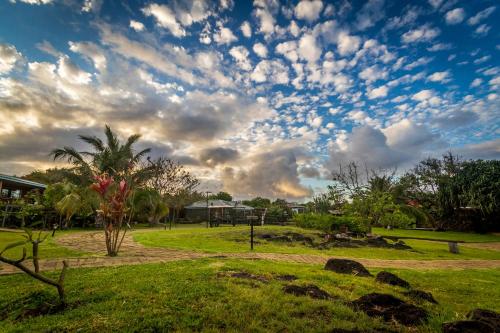 a cloudy sky above a park with a palm tree at Pikera Uri Eco Lodge in Hanga Roa
