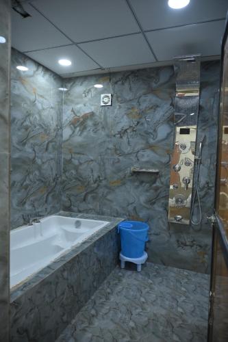 a bathroom with a tub and a blue bucket at Hotel The Grand Heritage Junagadh in Junagadh