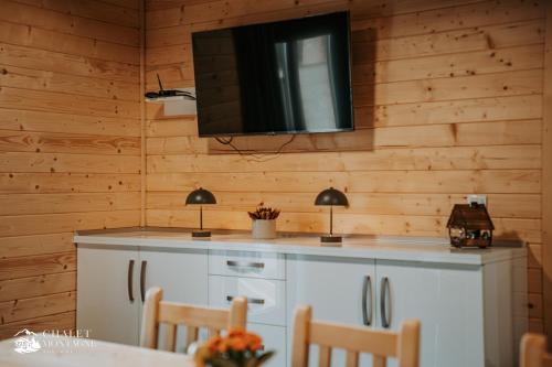 ein Wohnzimmer mit einem TV an einer Holzwand in der Unterkunft Chalet Montagne Borzont in Bucsin