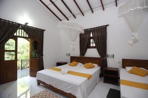 2 Betten in einem Zimmer mit weißen Wänden und Fenstern in der Unterkunft Scenic Cottage Sigiriya in Sigiriya