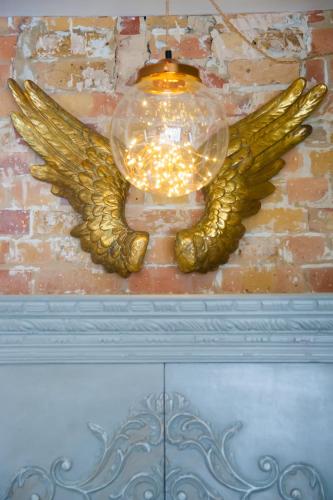 a gold angel wing light hanging from a brick wall at Rooms at number one in Broadstairs