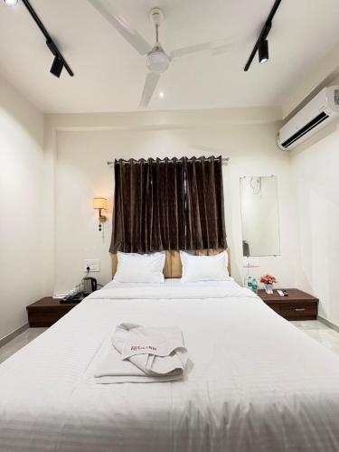 a bedroom with a large white bed with a window at Hotel Riva Inn in Miraj