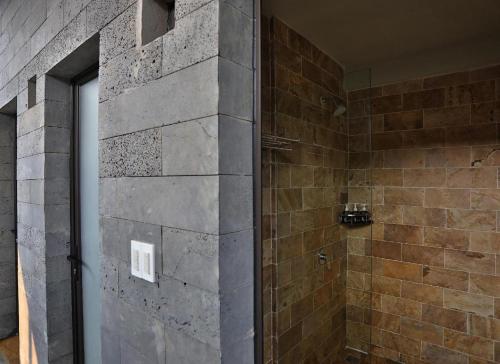 a bathroom with a shower with a stone wall at Pu Luong Hostel in Ải Hạ