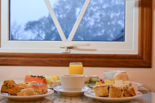 une table recouverte de assiettes de nourriture à côté d'une fenêtre dans l'établissement Hotel Renascença, à Gramado