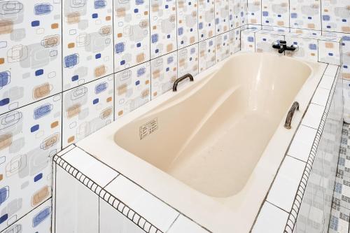 a white bath tub in a bathroom with tiles at RedDoorz Syariah Near Kantor Bupati Jepara in Jepara