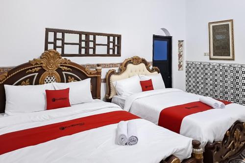 a bedroom with two beds with red and white sheets at RedDoorz Syariah Near Kantor Bupati Jepara in Jepara
