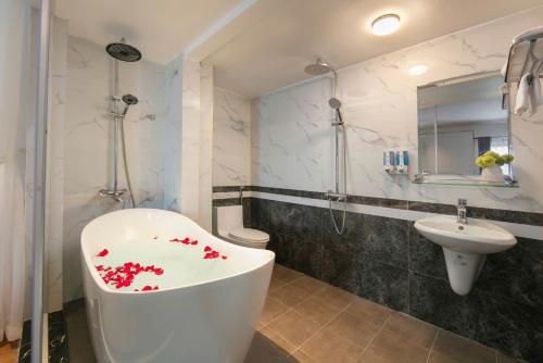 a bathroom with a white tub and a sink at Royal Hotel & Spa in Ðồng Ky